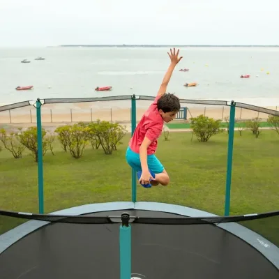 Enfant sautant sur un trampoline face à la mer
